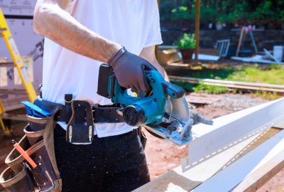 Worker cuts plastic vinyl siding to size before installing it with circular handsaw